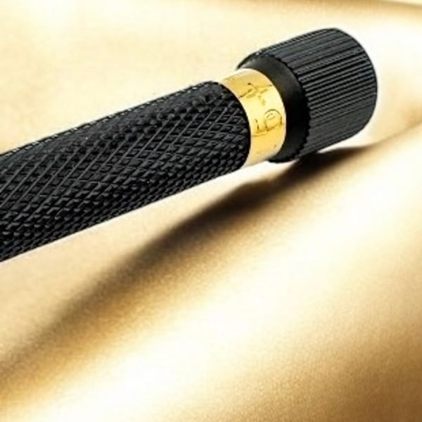 Close-up of gold adjustment ring and knurled black handle on gold satin backdrop