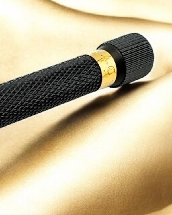 Close-up of gold adjustment ring and knurled black handle on gold satin backdrop