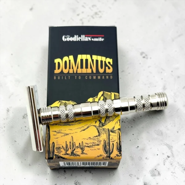 Dominus safety razor lying across its box with a double-edge blade fitted in the head