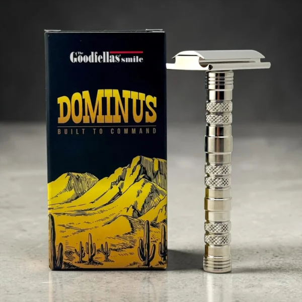 Dominus safety razor standing beside its Goodfellas' Smile presentation box on a grey studio background