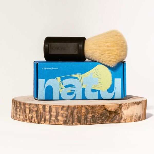NATU synthetic shaving brush in black resting on its retail box