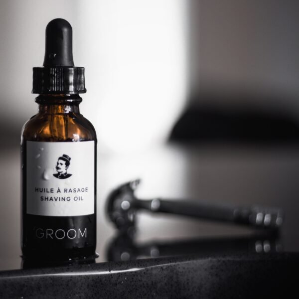 GROOM Shaving Oil 30 ml dropper bottle beside a safety razor