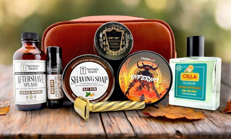 Shaving soaps, aftershaves and a razor with a leather toiletry bag on a wooden table with autumn leaves